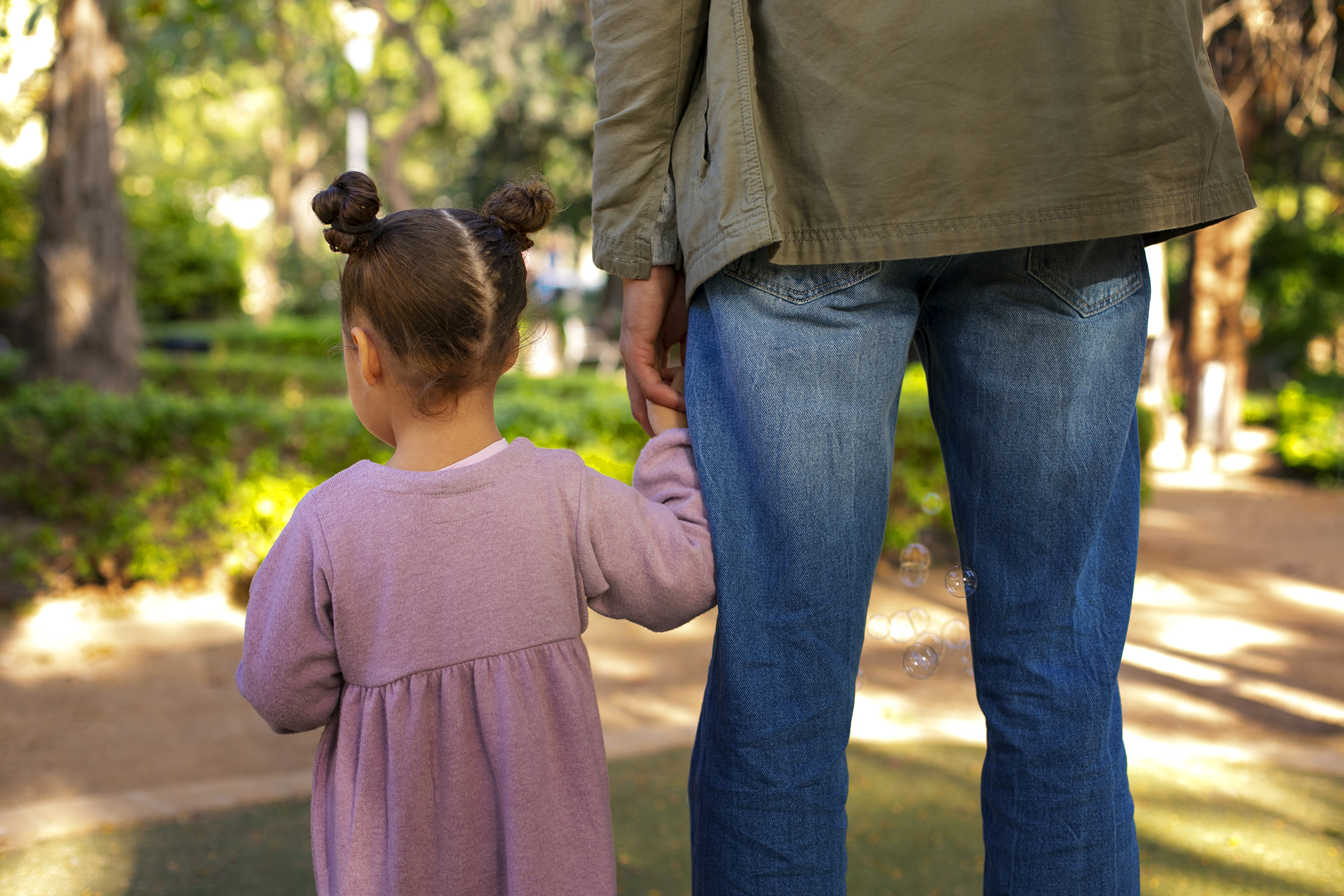 Criança de mãos dadas com um adulto em um parque